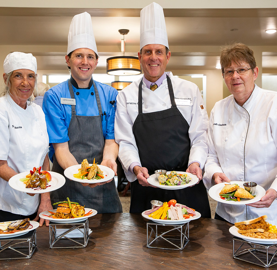 Chefs holding out plates of food.