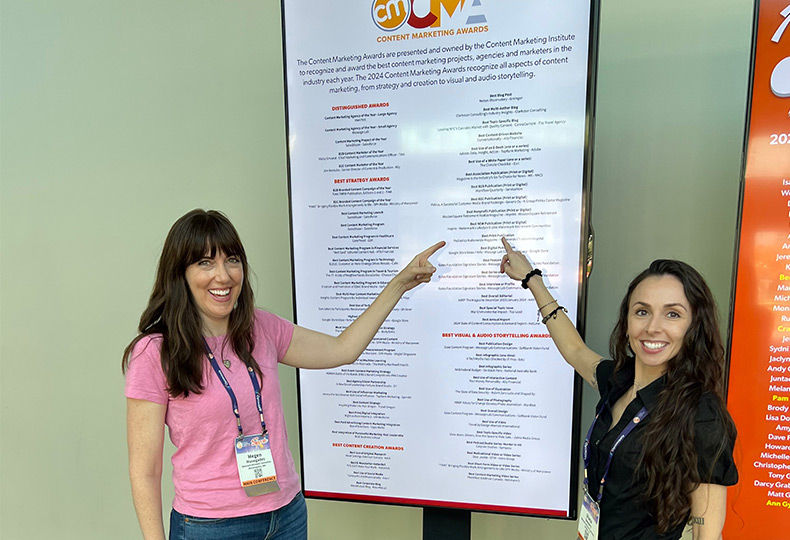 Two people pointing to a large board.