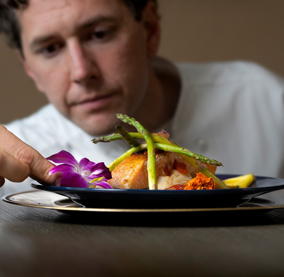 A chef placing a flower on a plate.