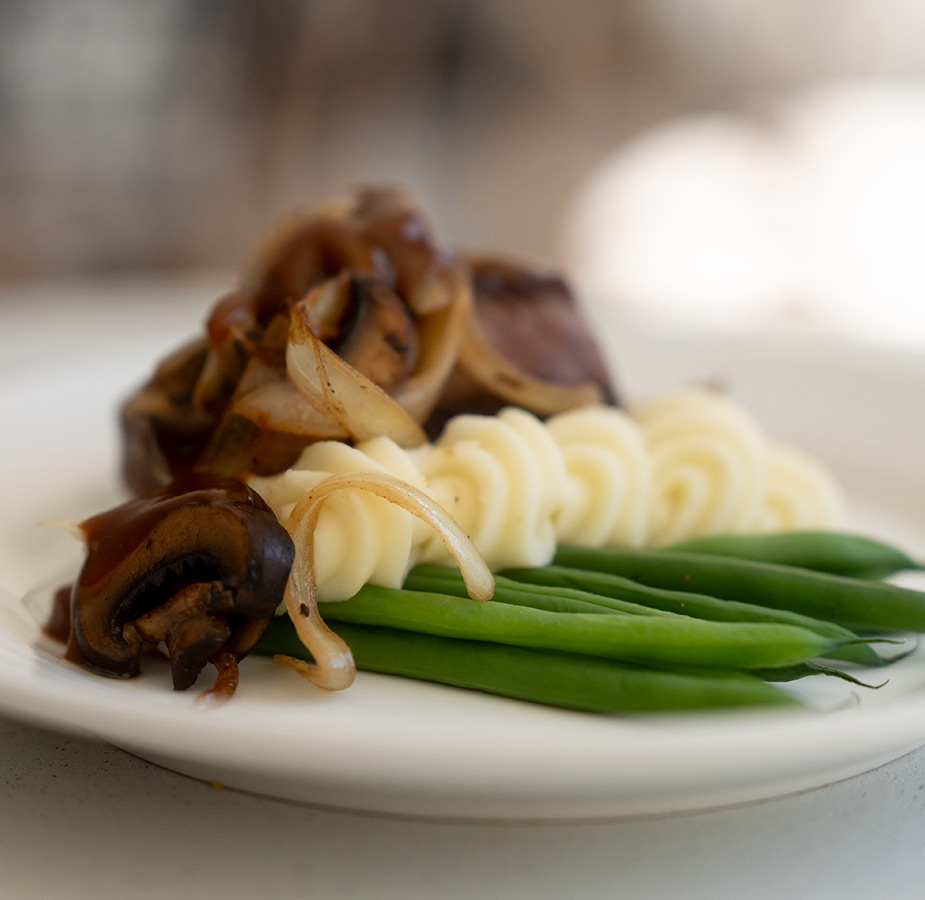A plate with steak, potatoes and green beans on it.