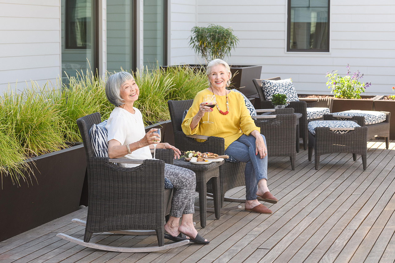 Two residents are drinking wine outside.