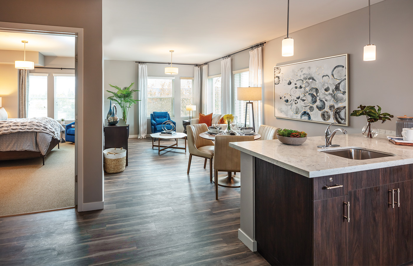 A fully furnished apartment kitchen looking into the living room.