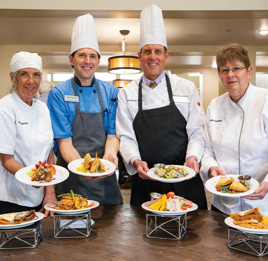 Four chef's showing plates of food.