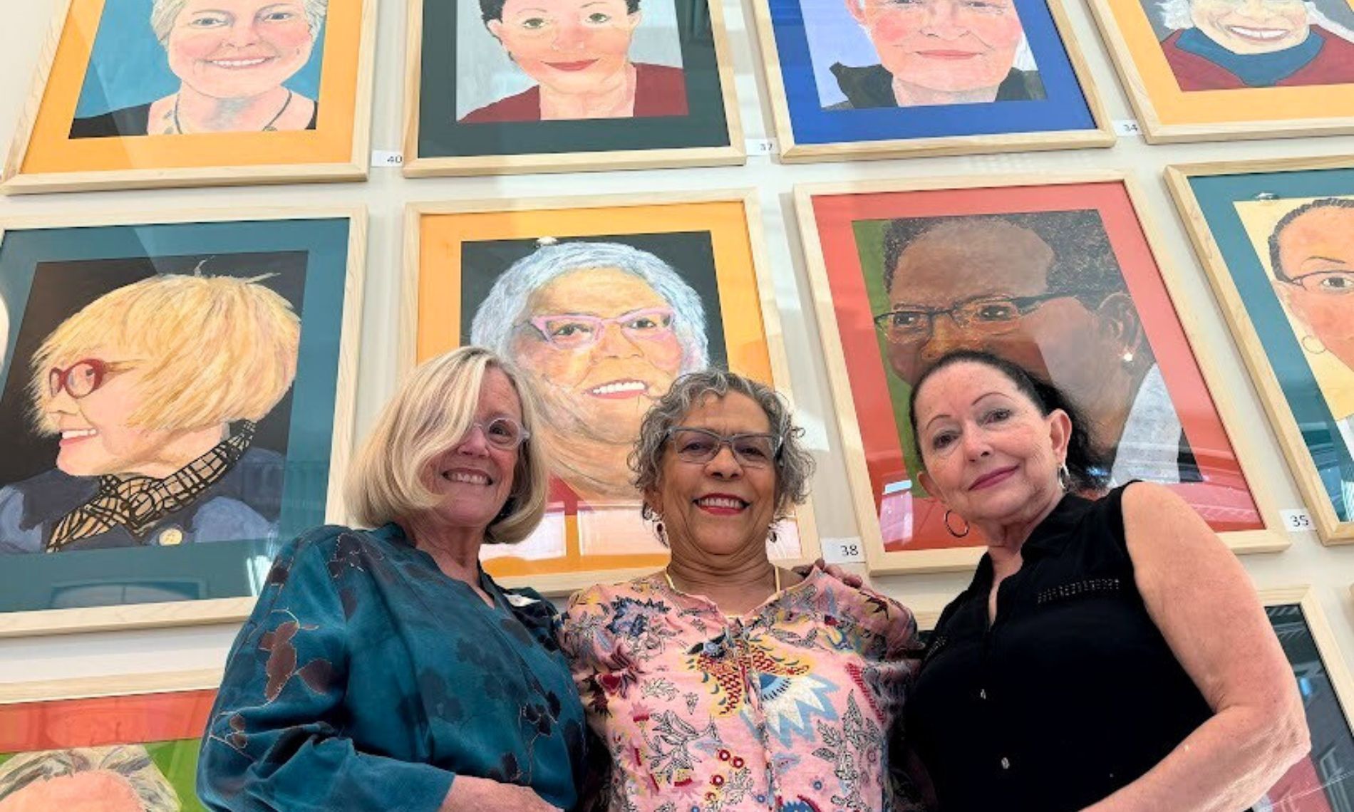 Feeling Our Age exhibit with three people standing in front of portraits.
