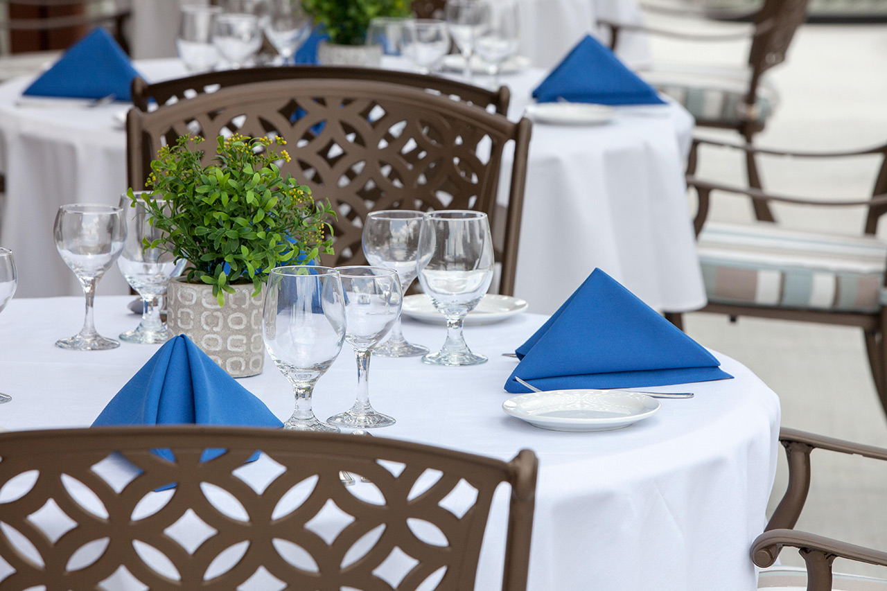Set tables with blue napkins and chairs.
