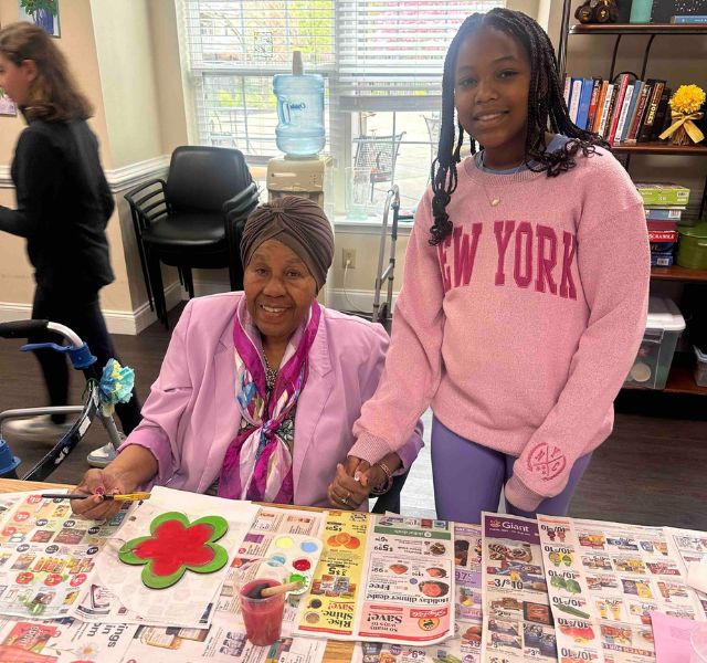 Rockland-Painting A resident painting and a young person standing next to the resident.