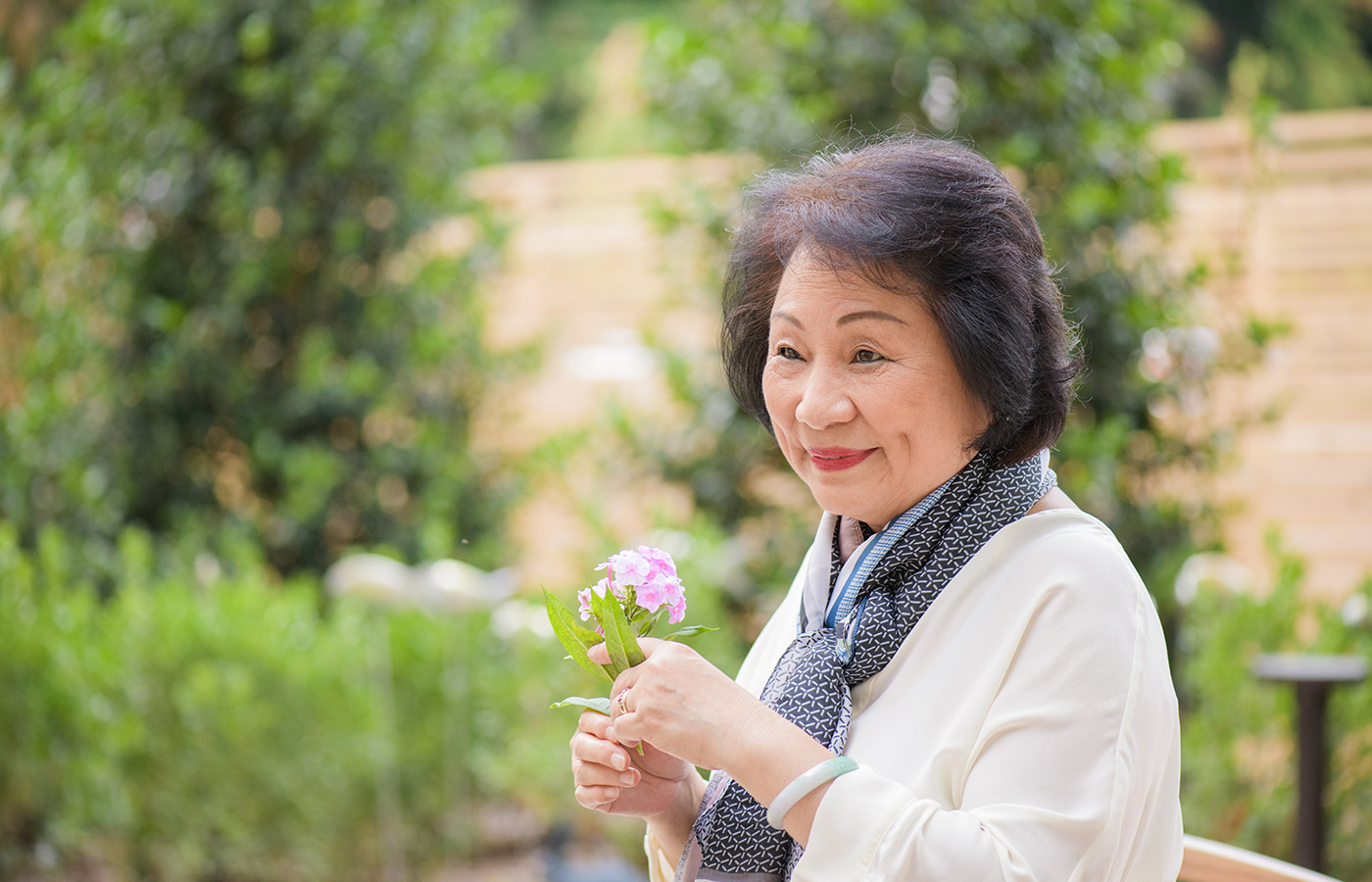 A resident is holding flowers outside.