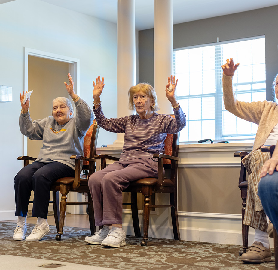 People sitting in chairs doing exercise.