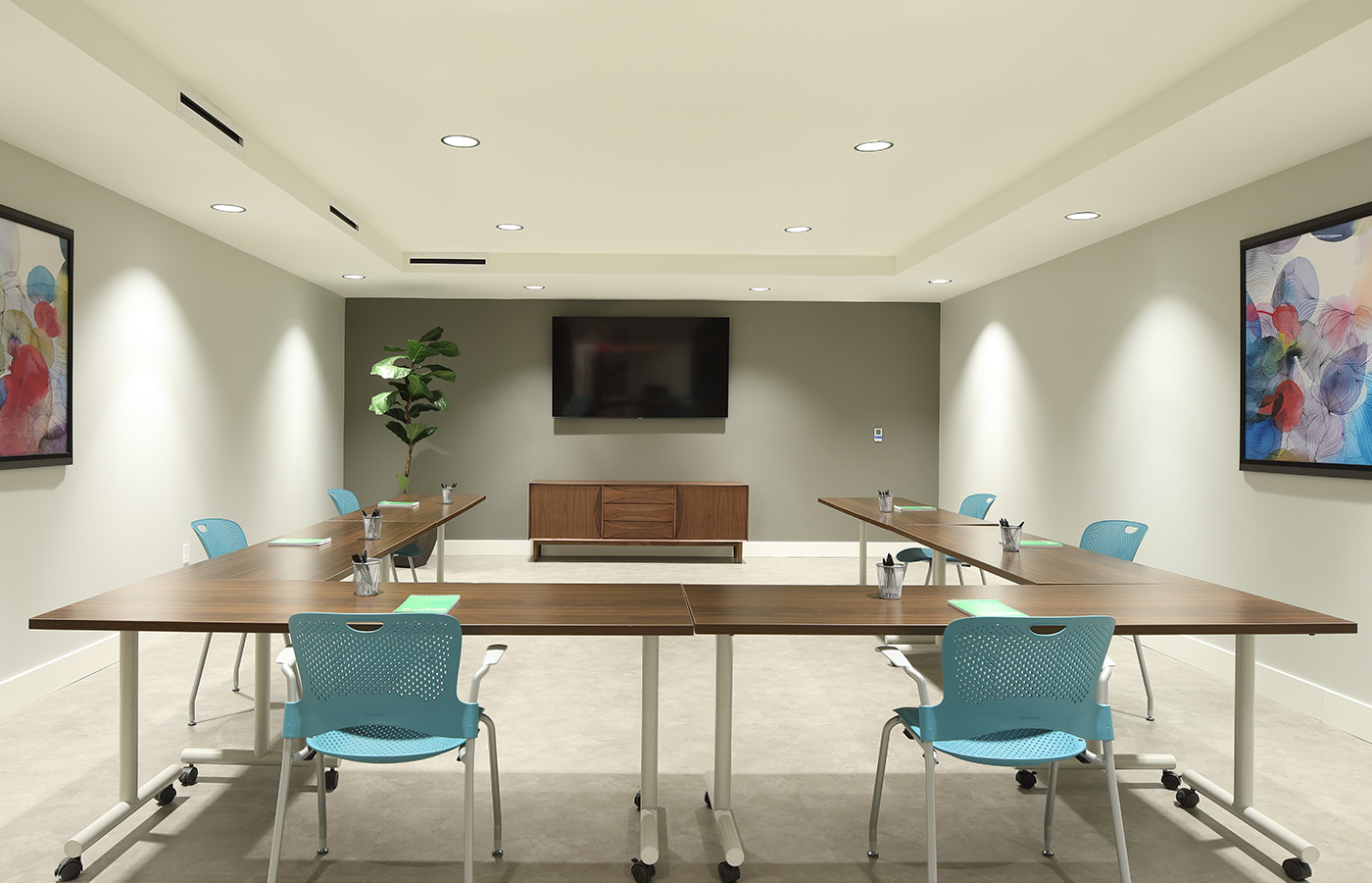 A conference room with a table, chairs, and monitor on the wall.