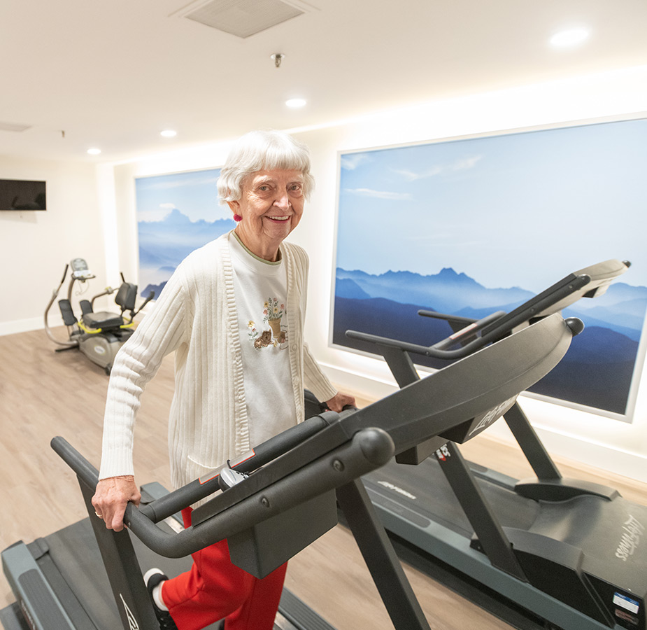 A resident is on a fitness machine in the gym.