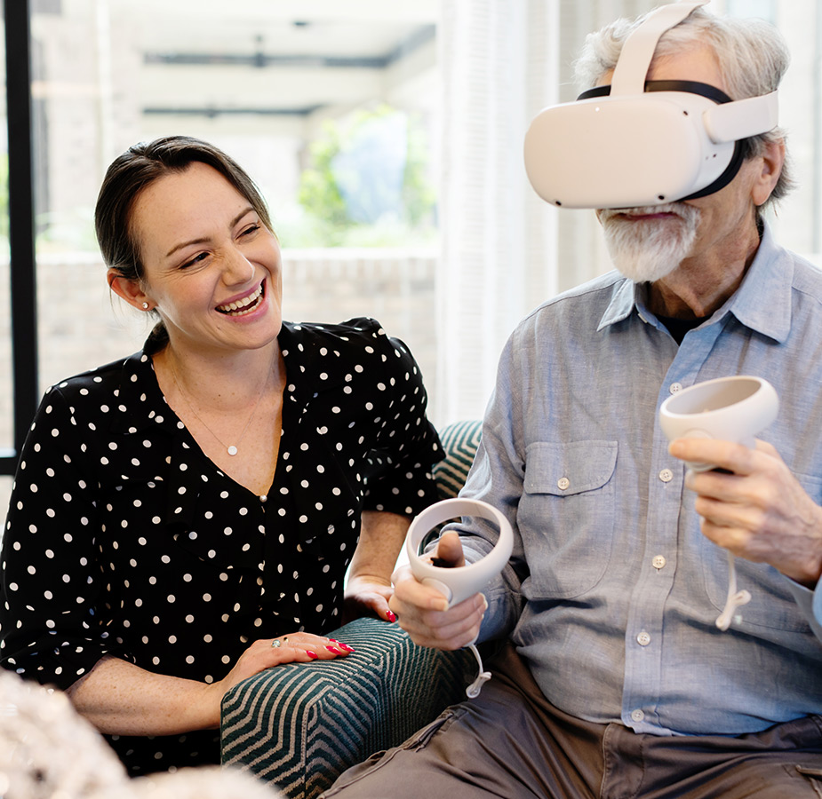 A Naya caregiver helping a person with a VR headset on.