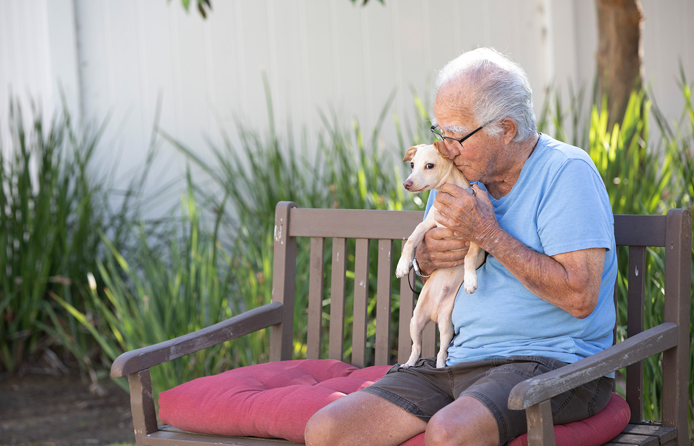 A resident sitting on a bench outside with his dog.