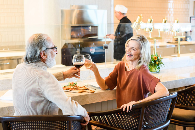 Two residents are sitting at a bar enjoying glasses of wine.