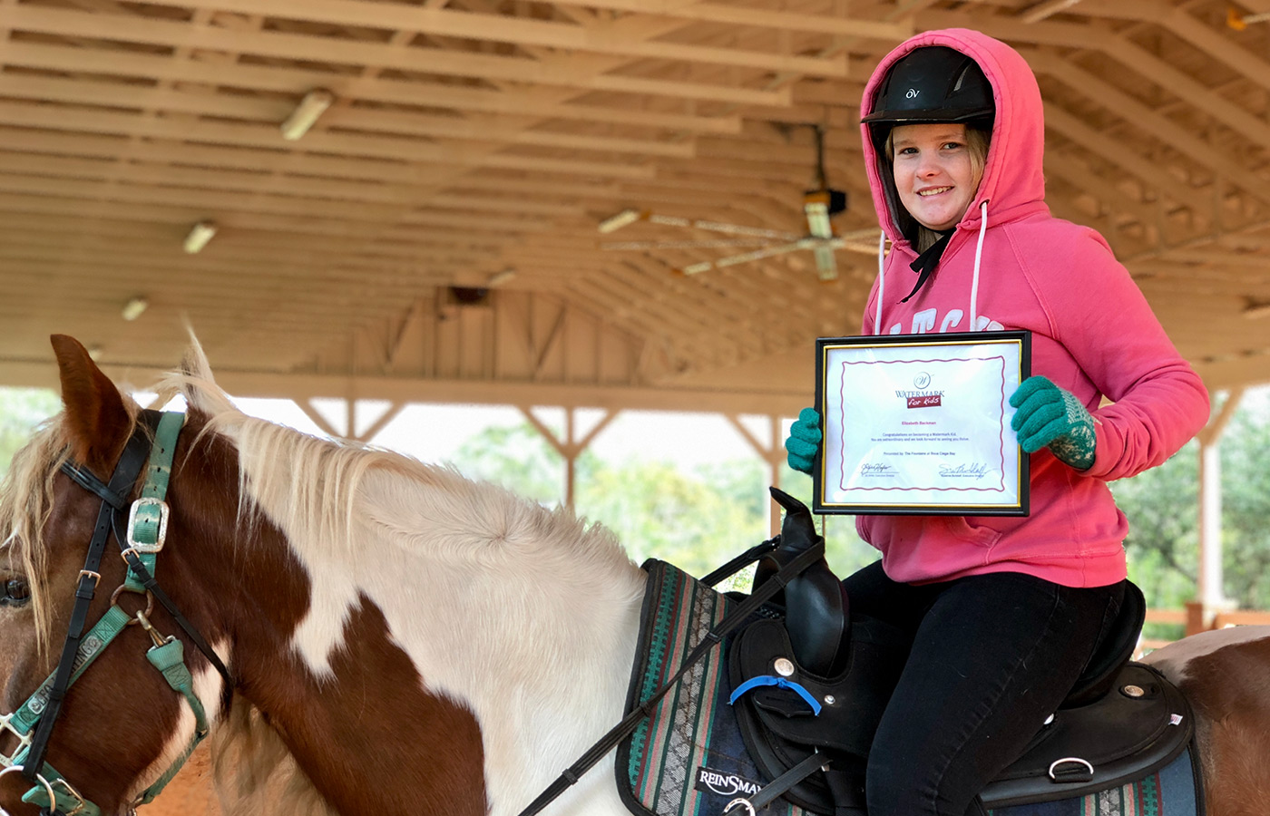 kid riding a horse holding a certificate