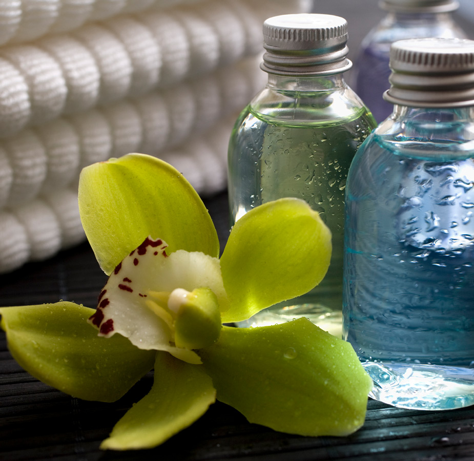 Glass spa bottles next to a flower.