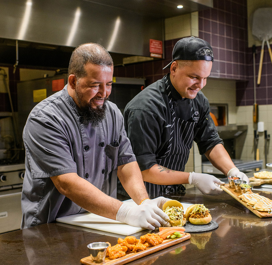 Two chefs in a kitchen preparing food.