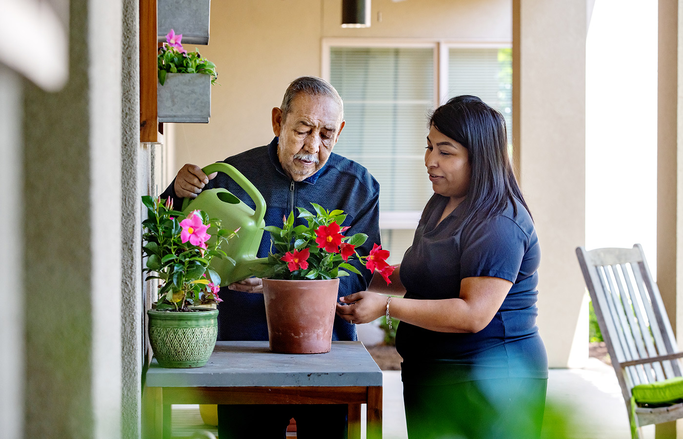 A naya caregiver helping a resident water plants.