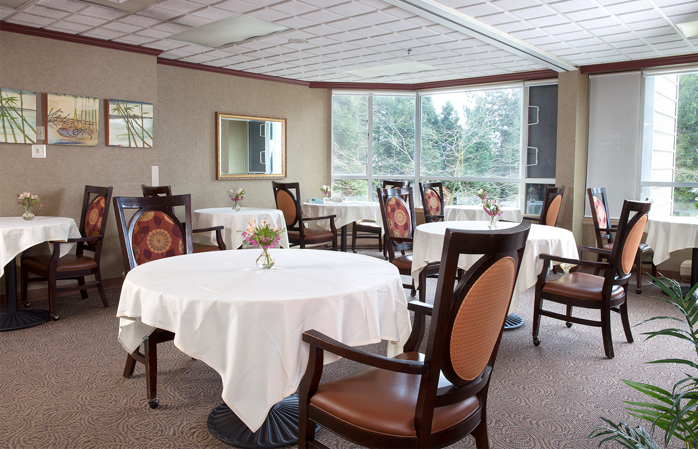 dining area with tables, bright windows and white tablecloths