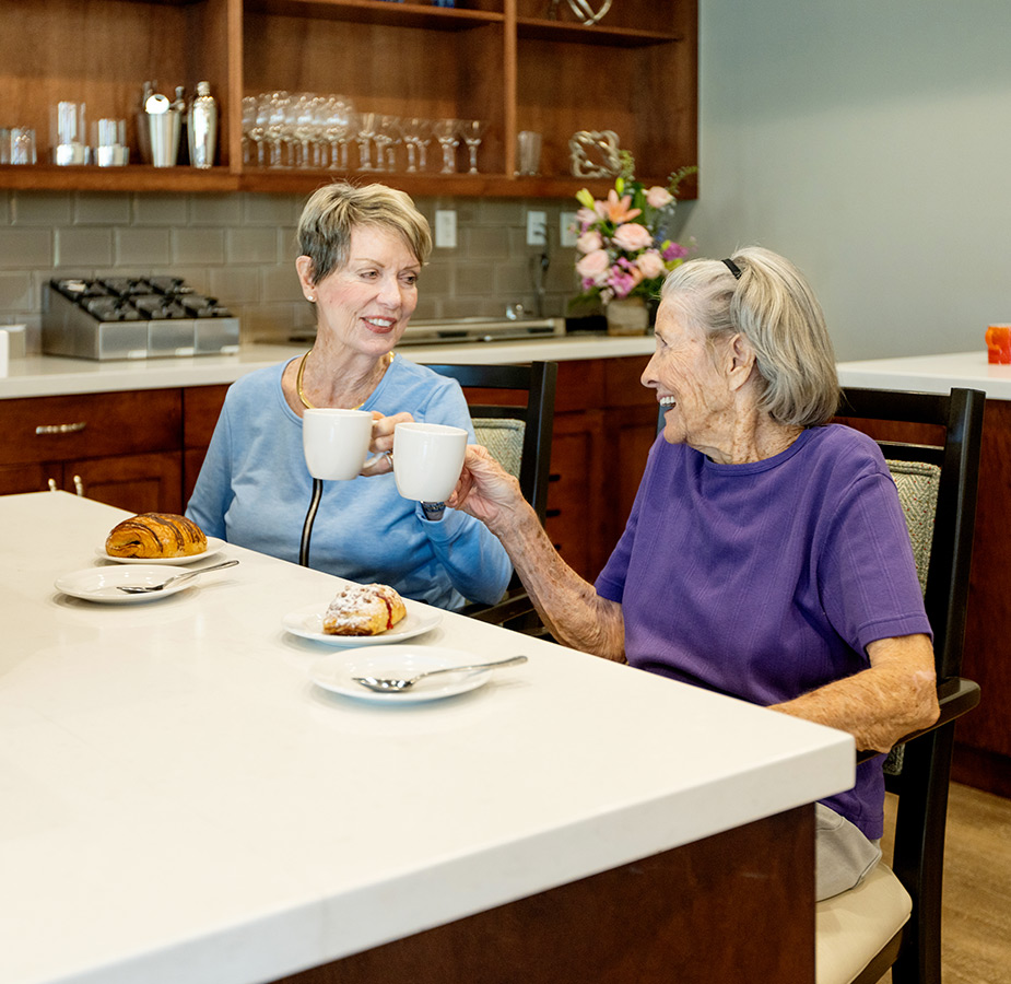 Two residents enjoy a croissant and cup of coffee.