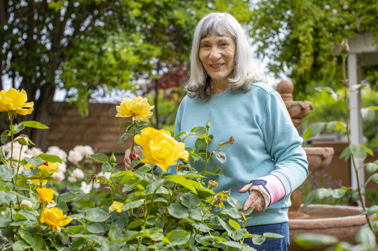 A resident is standing by yellow flowers 
