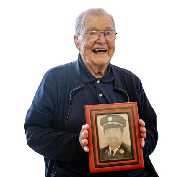 A resident is holding a photo from when he was a firefighter.
