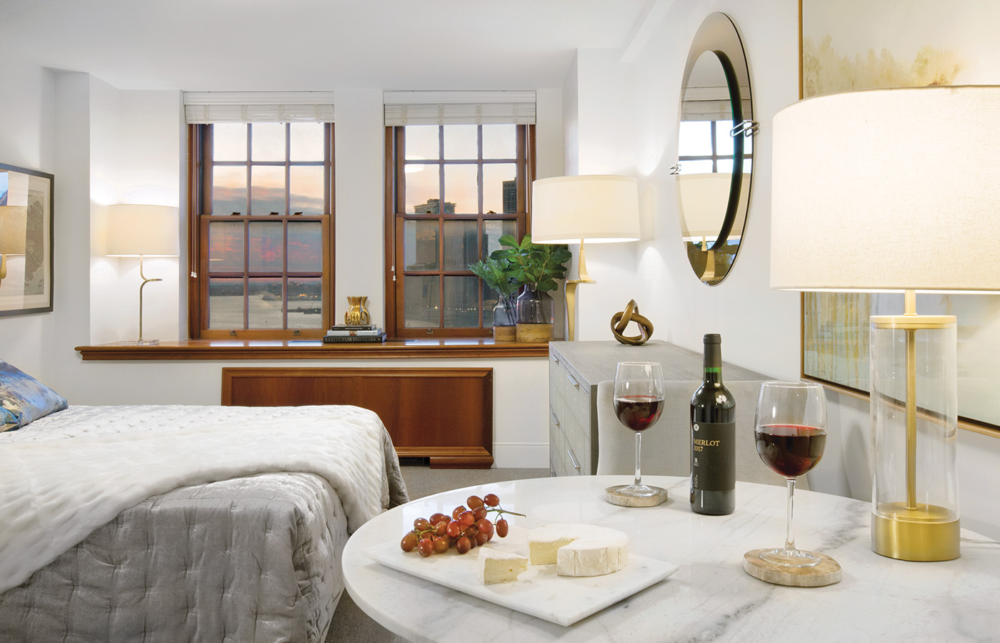 Furnished bedroom with bed, seating area, and soft lighting.