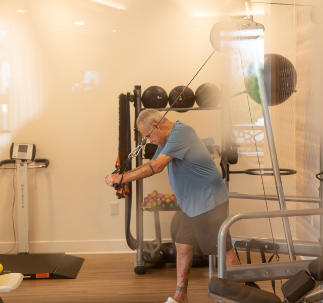 Resident standing and using weights in fitness center.