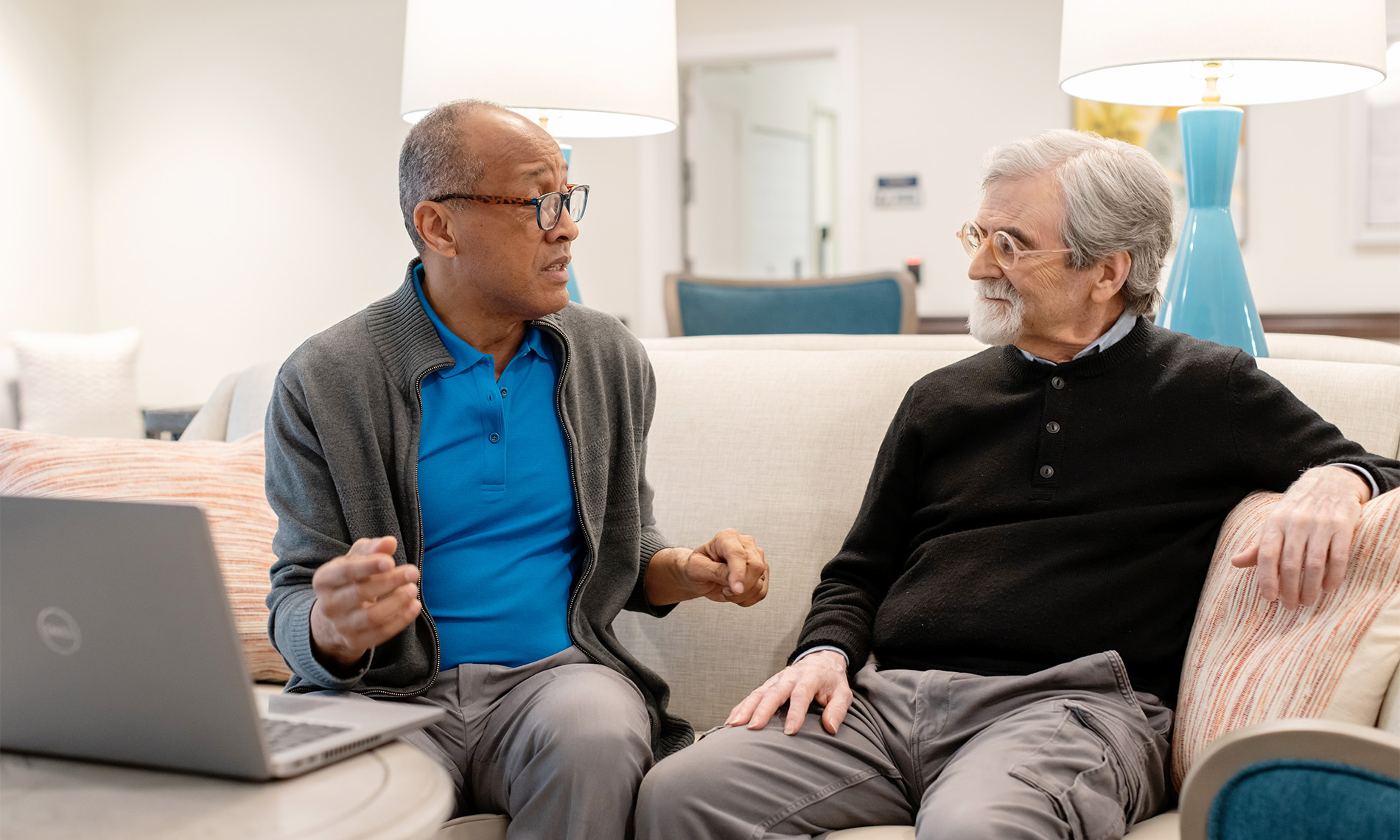 Two people talking with a computer.