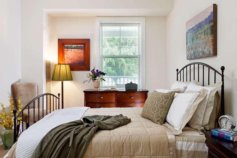 Furnished bedroom with bed, table, and window.