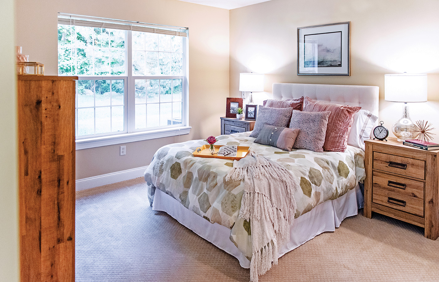 Furnished bedroom with bed, drawers, and soft lighting.