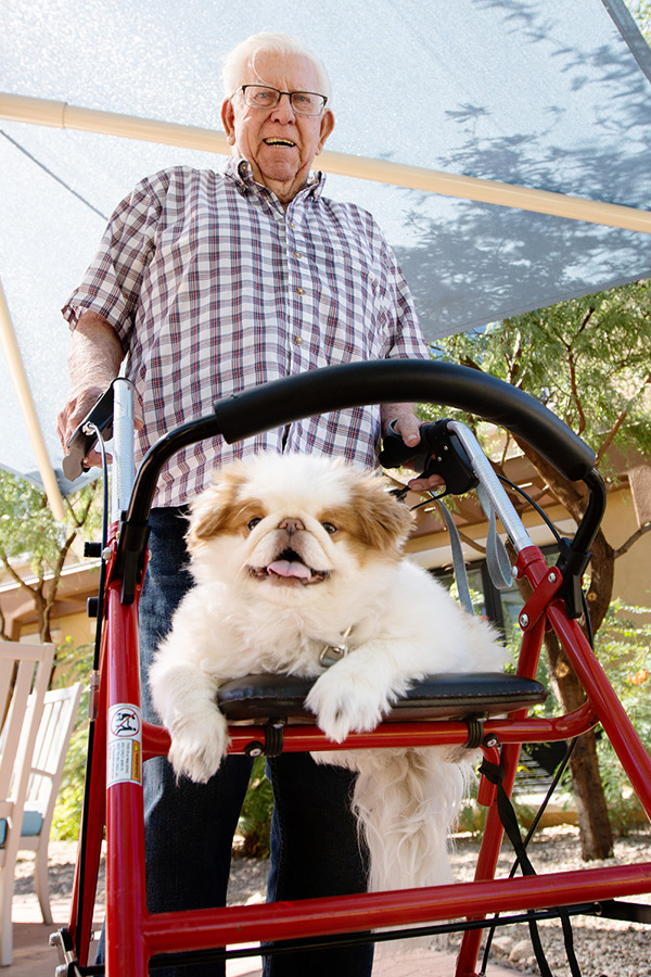 A resident with their dog on resting on their walker.