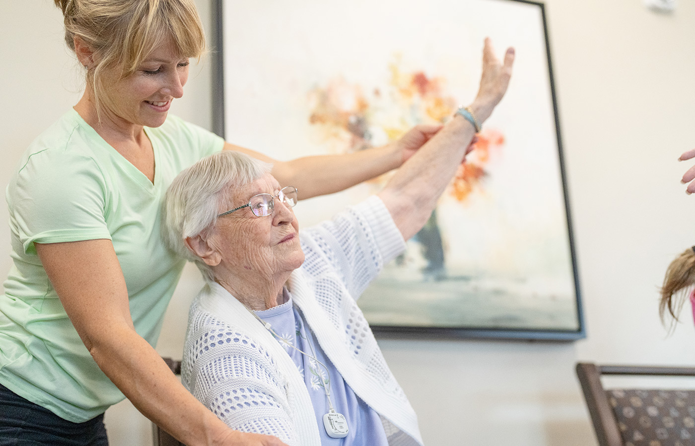 Physical therapist helps resident stretch out arm.