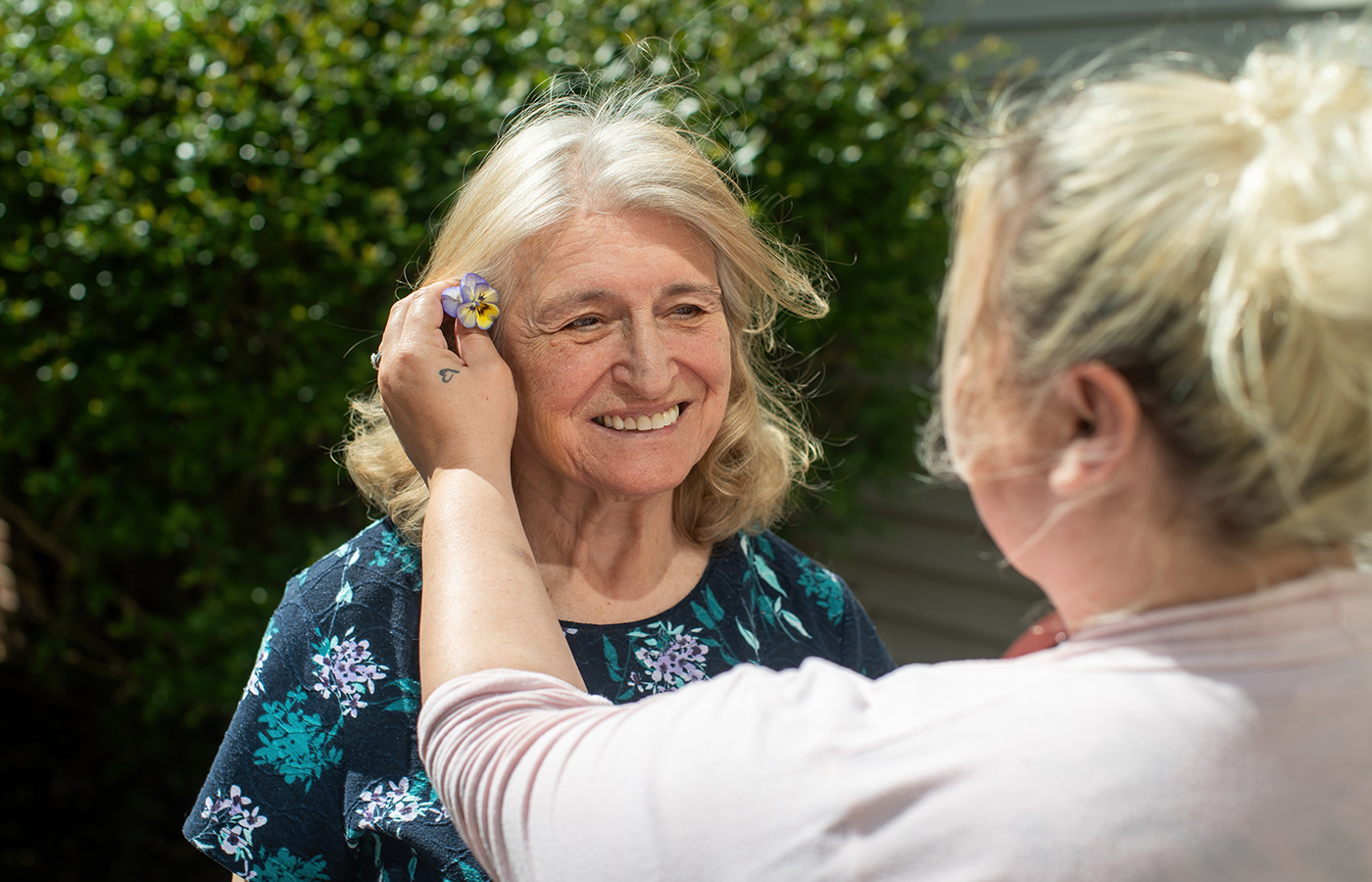 A naya caregiver putting a flower in a resident's hair.