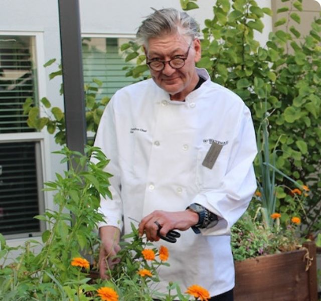 Chef Ron is outside trimming plants.