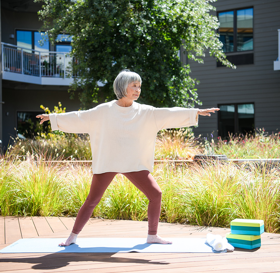 Resident does warrior pose in yoga on a mat.