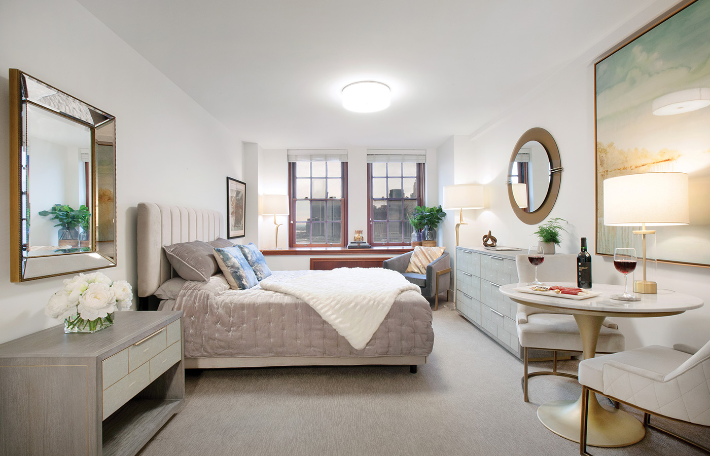 Furnished bedroom with bed, seating area, and soft lighting.