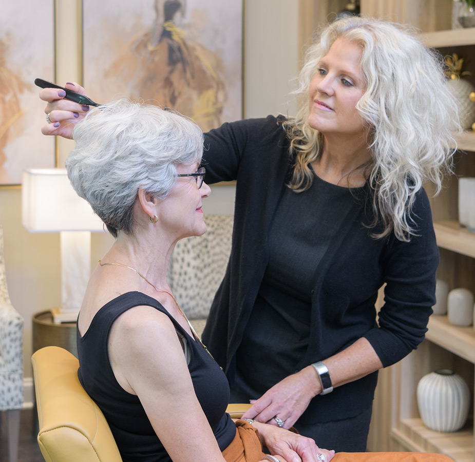 A resident is sitting on a chair getting their hair styled at the salon.