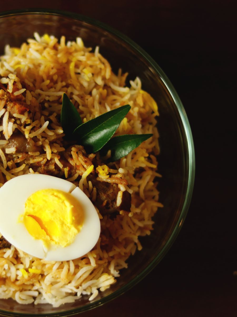 A bowl of chicken biryani with a boiled egg on top.