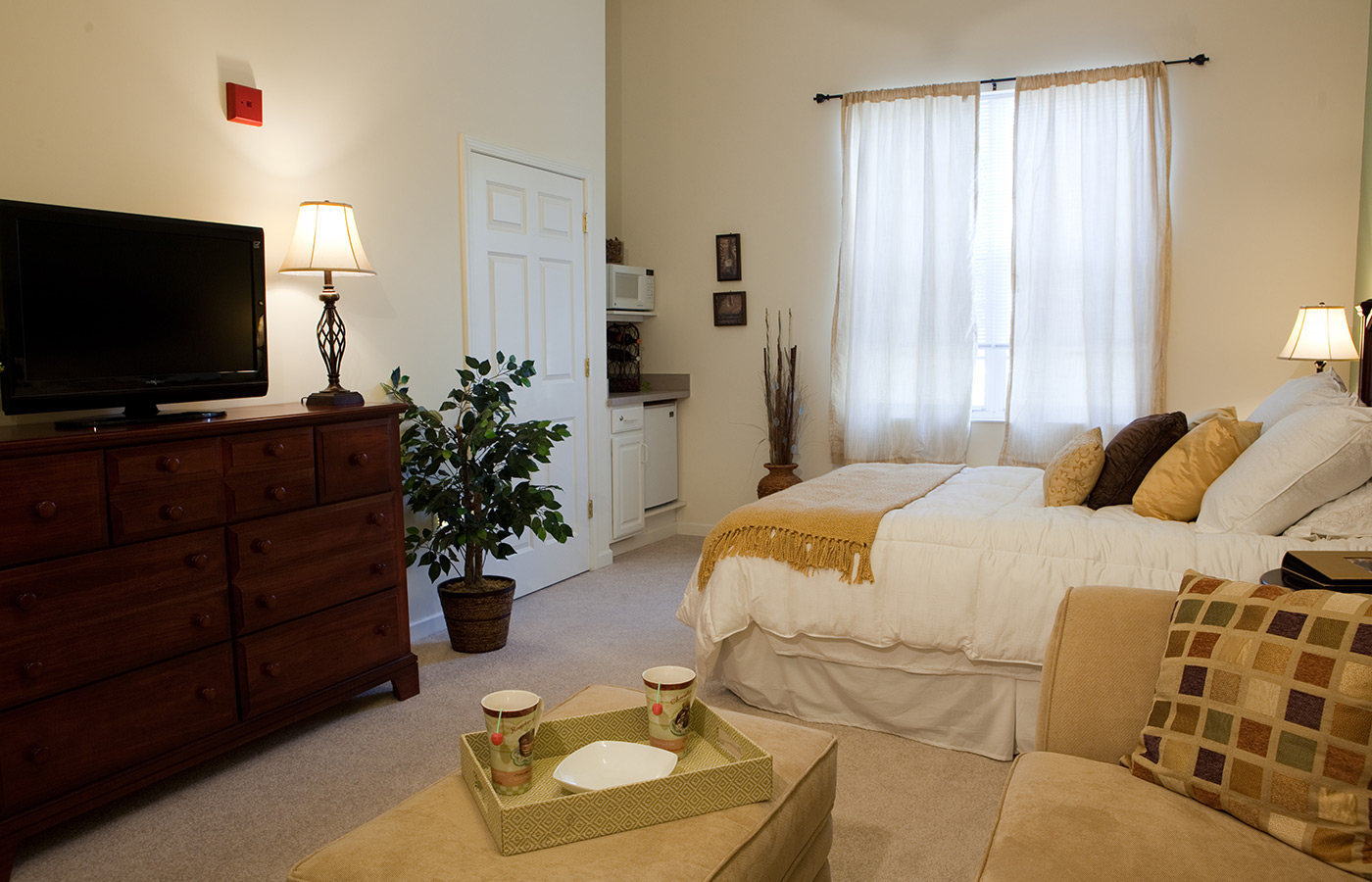 bedroom with sofa, bed, entertainment center with a tv on top and a bright window