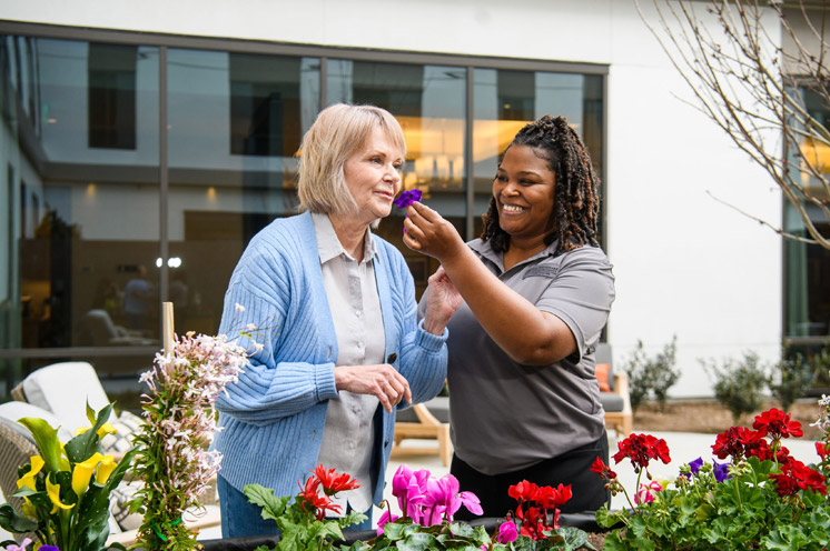 Two residents are outside looking at flowers.
