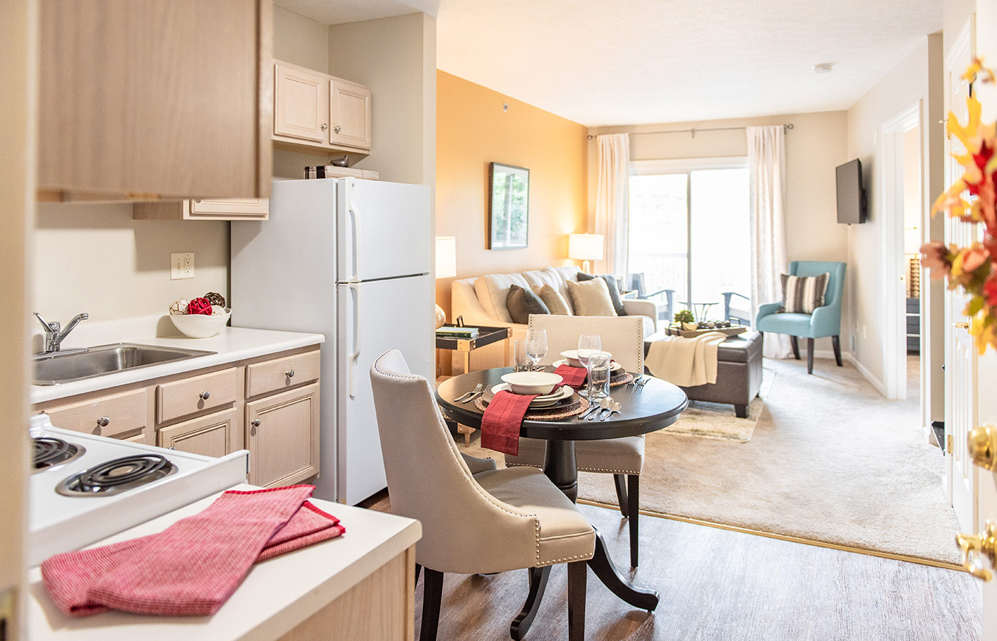 Furnished kitchen with table, cabinets, and refrigerator.