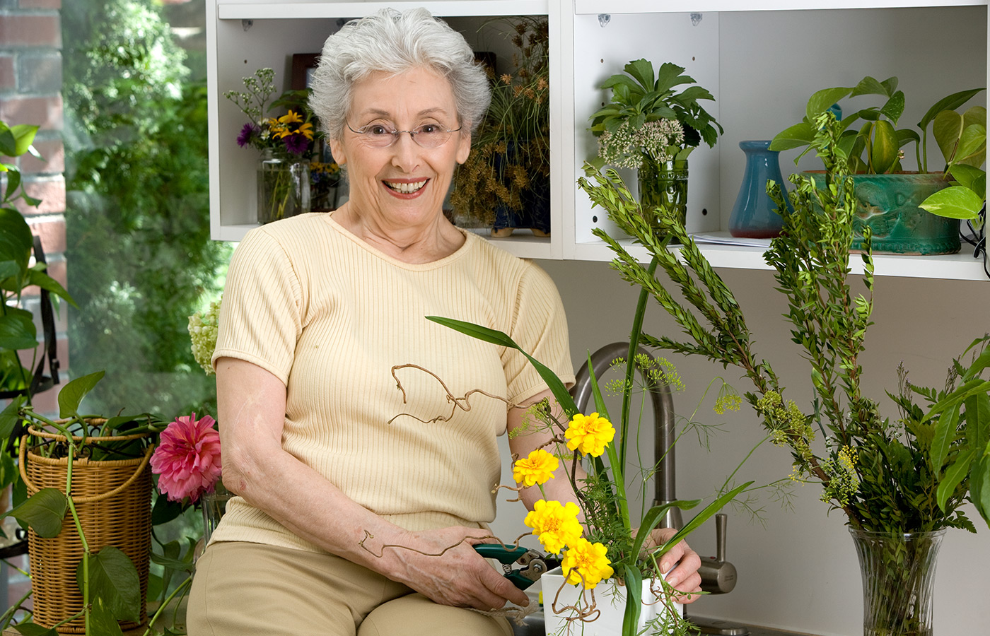 resident smiling and watering a pot of yellow flowers