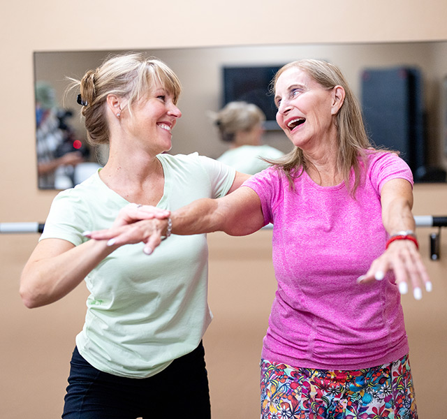 A caregiver is assisting a resident in a fitness class.