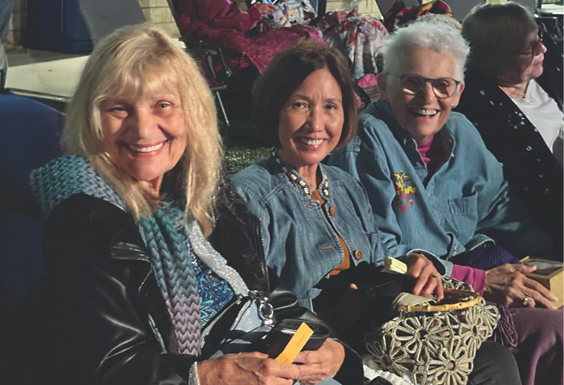 Three people smiling for camera at night.