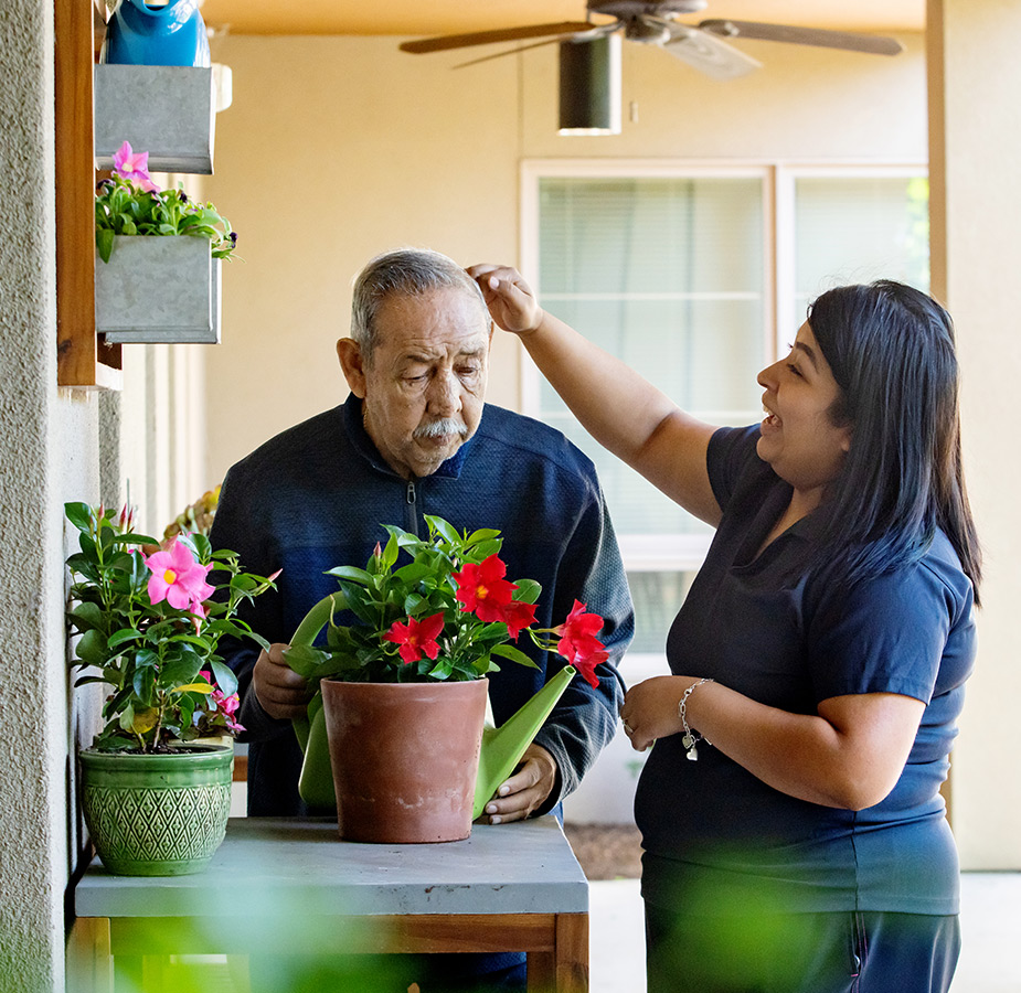 A naya caregiver helping a resident water plants.