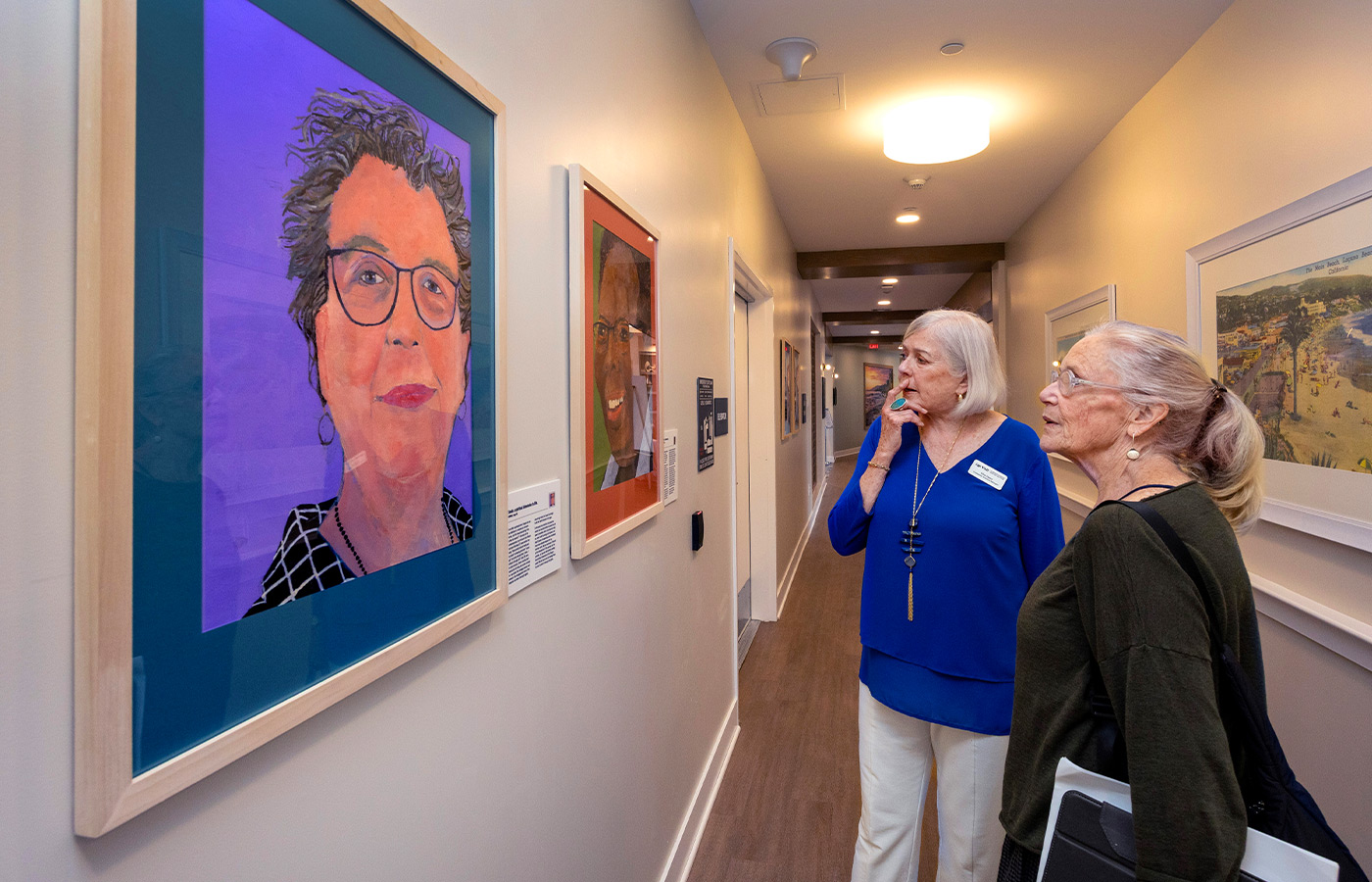People looking at paintings on the wall.