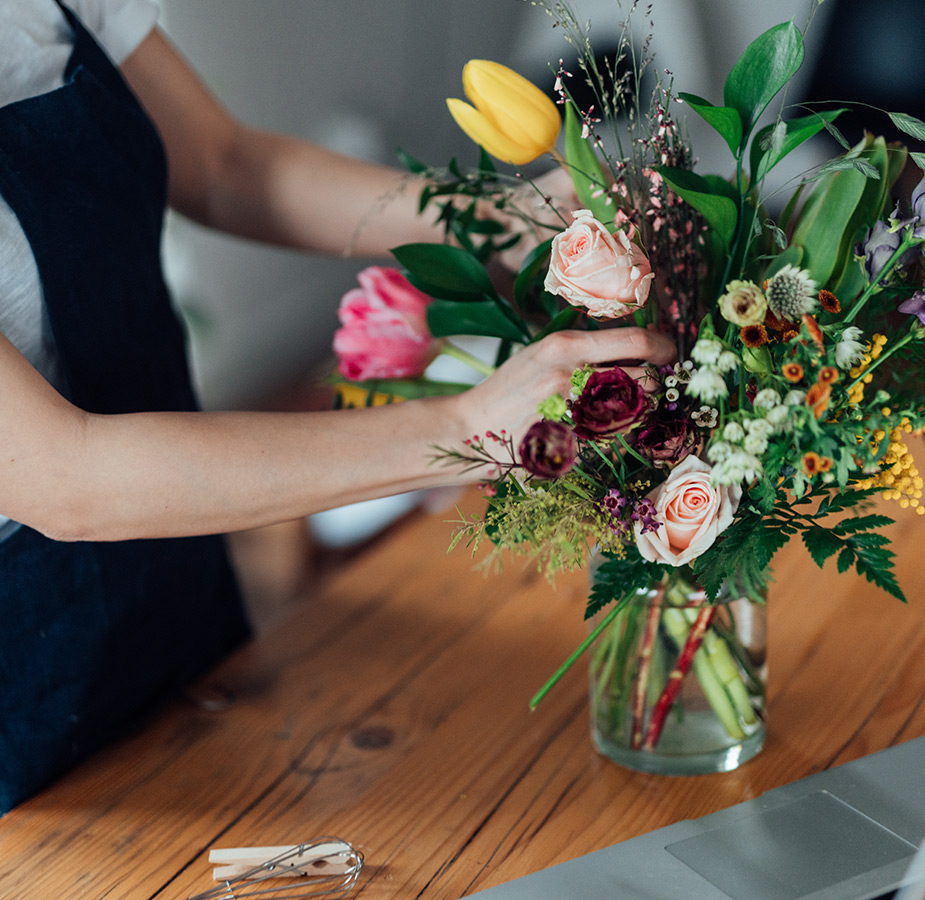 A person arranging flowers in a vase.