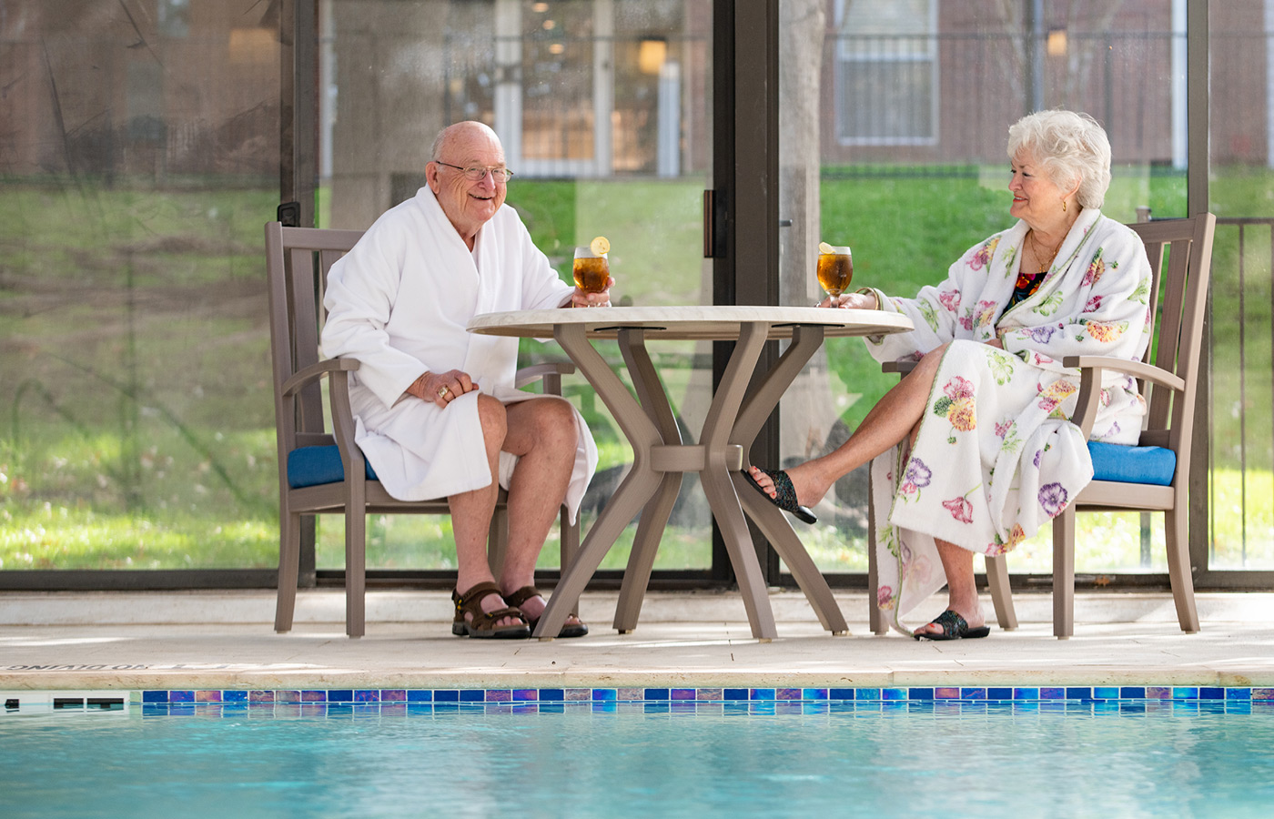 couple wearing robes enjoying drinks by the pool 
