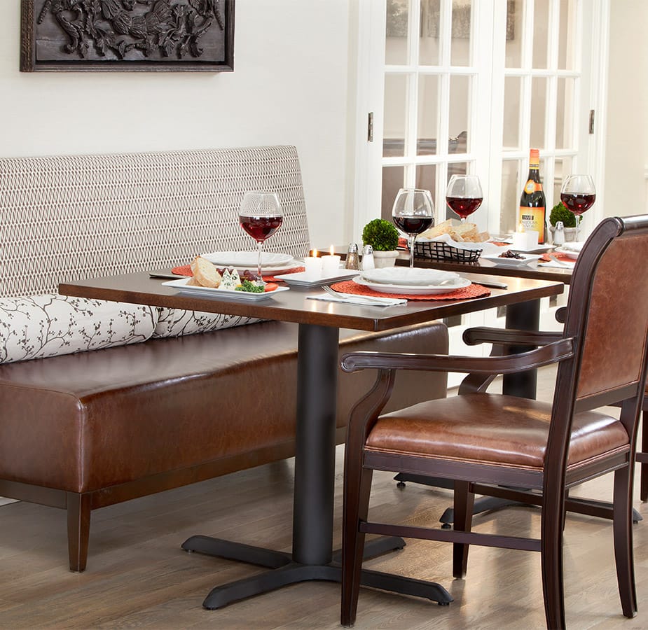 Dining table set with plates and wine glasses and chairs.