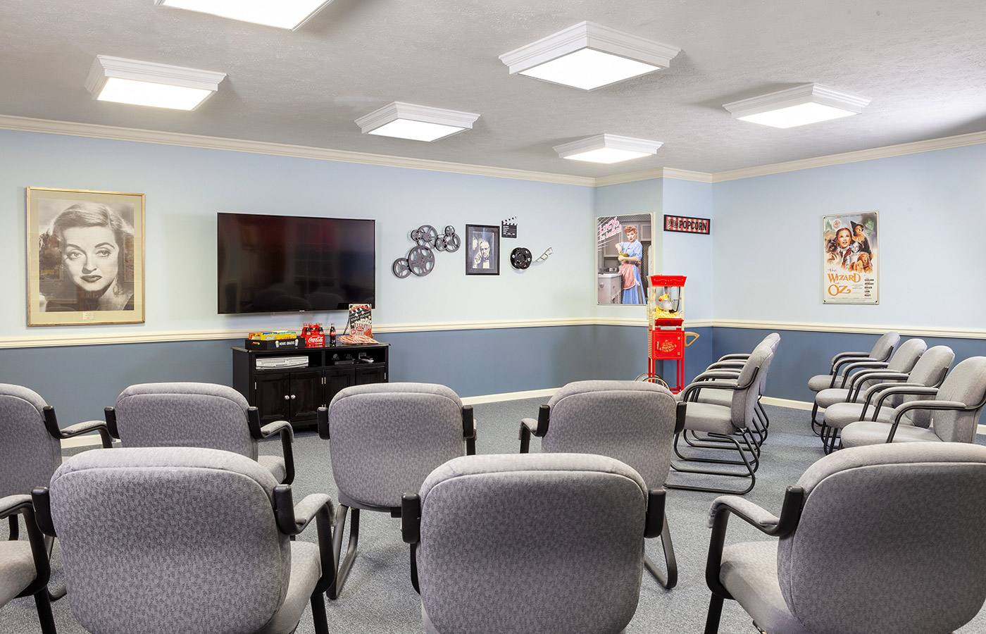 Theater room with television screen and chairs.